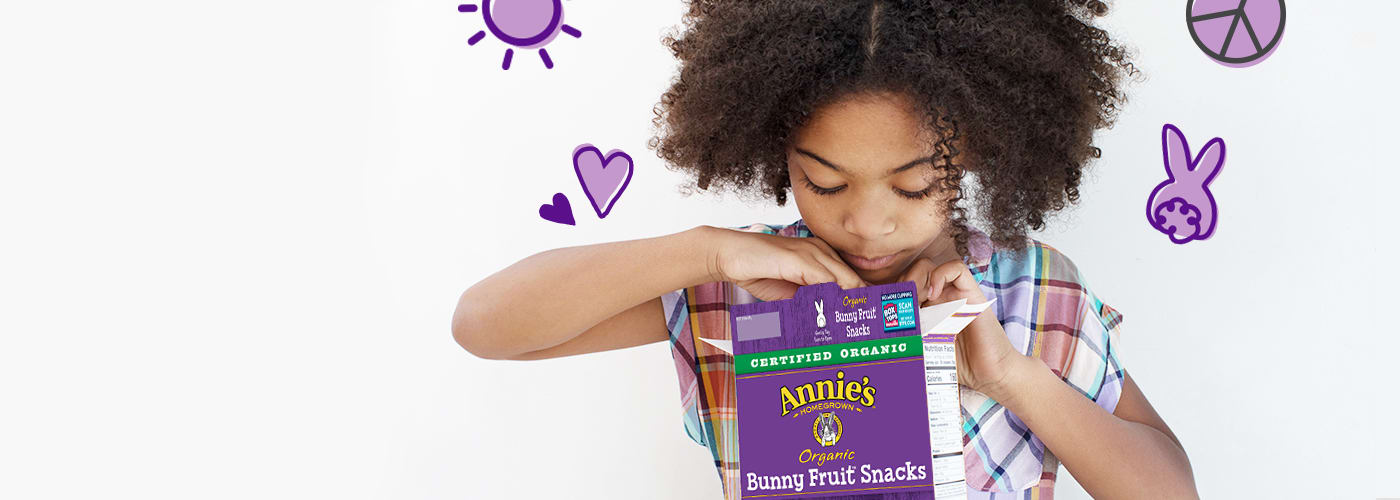 Little girl reaching into box of Annie's Fruit Snacks