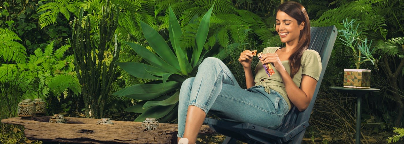 Girl Sitting in a chair eating a Fruit and Nut bar