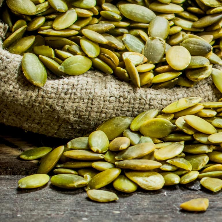 A burlap sack of green pumpkin seeds.