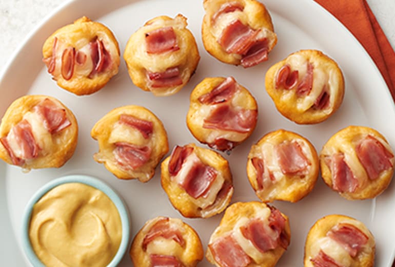 bacon-cheddar hasselback biscuit bites on a round serving tray