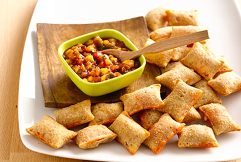 a bowl of mango salsa surrounded by pizza rolls