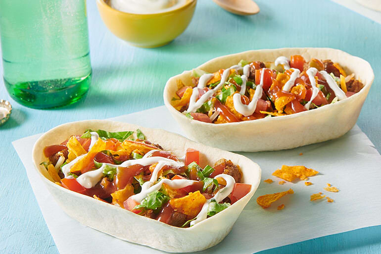 A tortilla shaped as a bowl with taco ingredients in the middle on a table