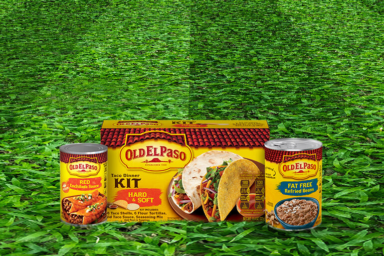 A green field of grass with three Old El Paso products are placed on the field