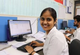 Mujer joven sonriendo a la cámara mientras usa la computadora