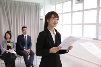 Woman holding documents in front of two people