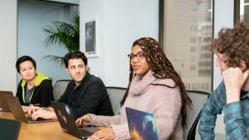 Young people on laptops in a classroom