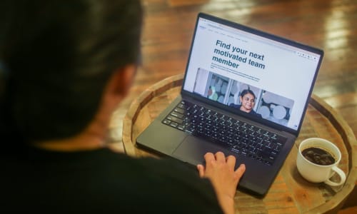 A person uses a laptop displaying Generation Australia’s employer webpage, featuring the message “Find your next motivated team member” and information about hiring job-ready graduates.