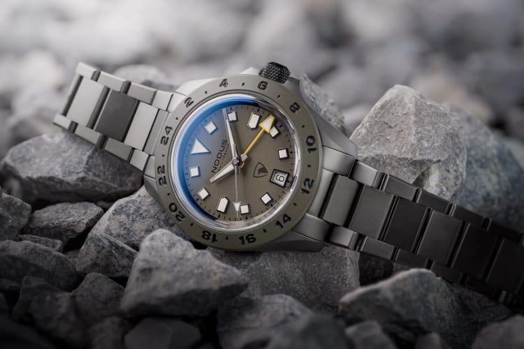 A close-up shot of a Nodus watch with a bold, clean design on a wooden table.