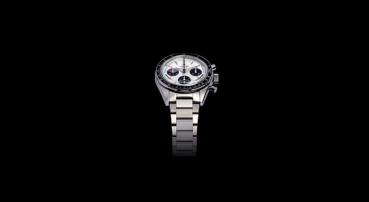 Close-up of a vintage-inspired Lorier watch with a stainless steel case and mesh bracelet on a wooden table.