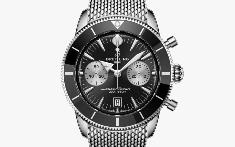 Breitling SuperOcean chronograph watch with black dial, silver subdials, and stainless steel mesh bracelet.