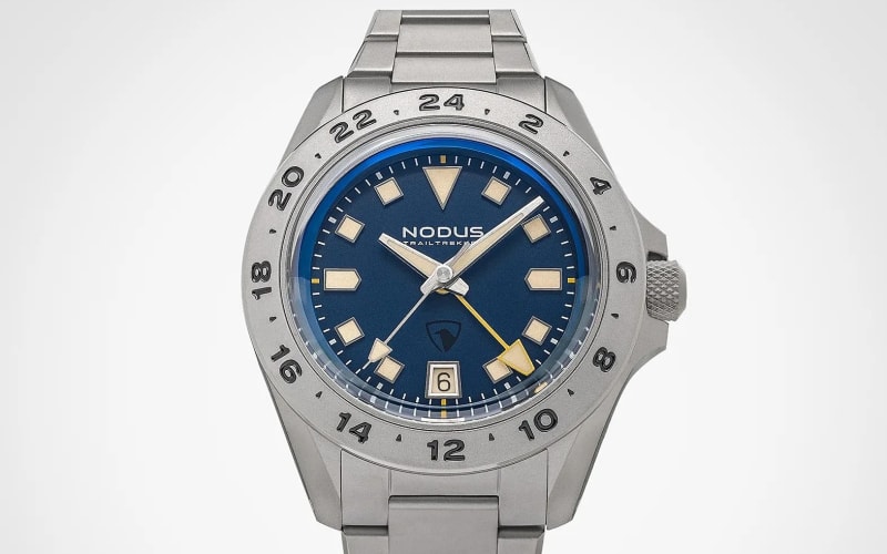 Silver metal wristwatch with blue dial, beige hour markers, date window at 6 o'clock, and 24-hour bezel.