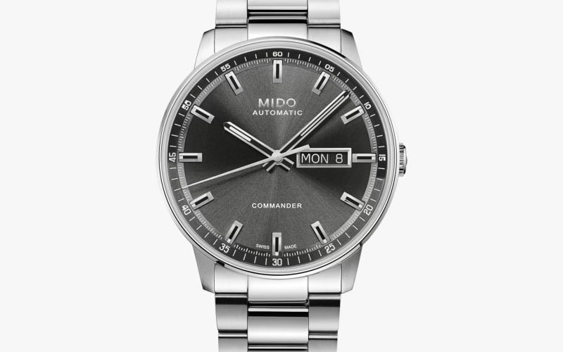 Silver stainless steel Mido Commander wristwatch with a dark gray sunburst dial and day-date display.