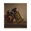Flacon de parfum par Anfas (Ghala Extrait) avec un bouchon doré orné et du verre vert, 100 ml, à côté d'une sculpture en pierre rustique.