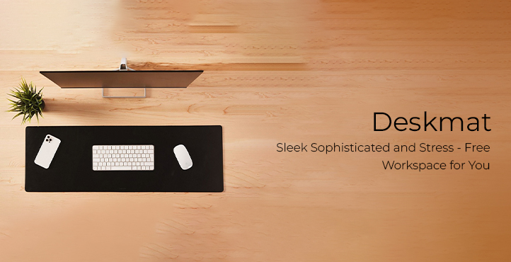 computer equipments on top of black desk mat infront of a desktop on a brown table