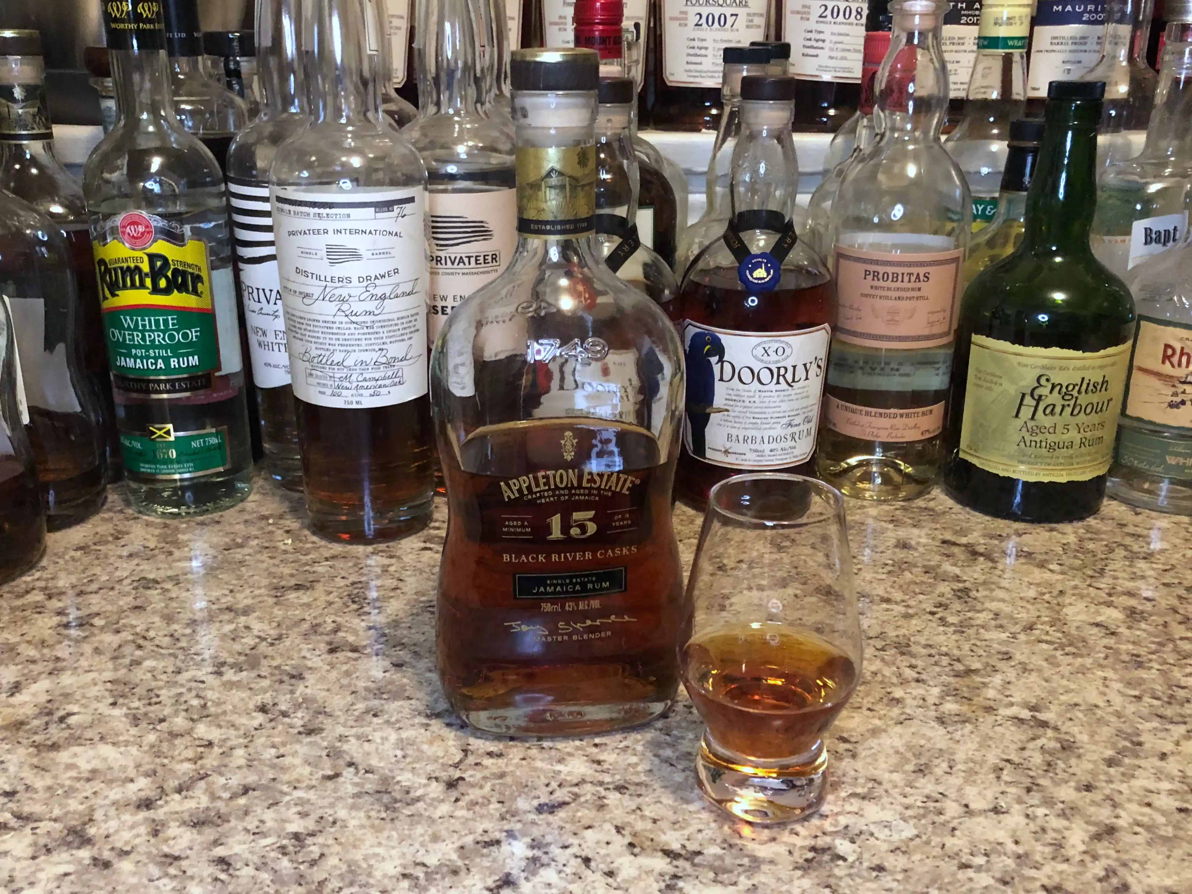 Black Tot rum bottle on a counter next to a snifter with rum poured in it