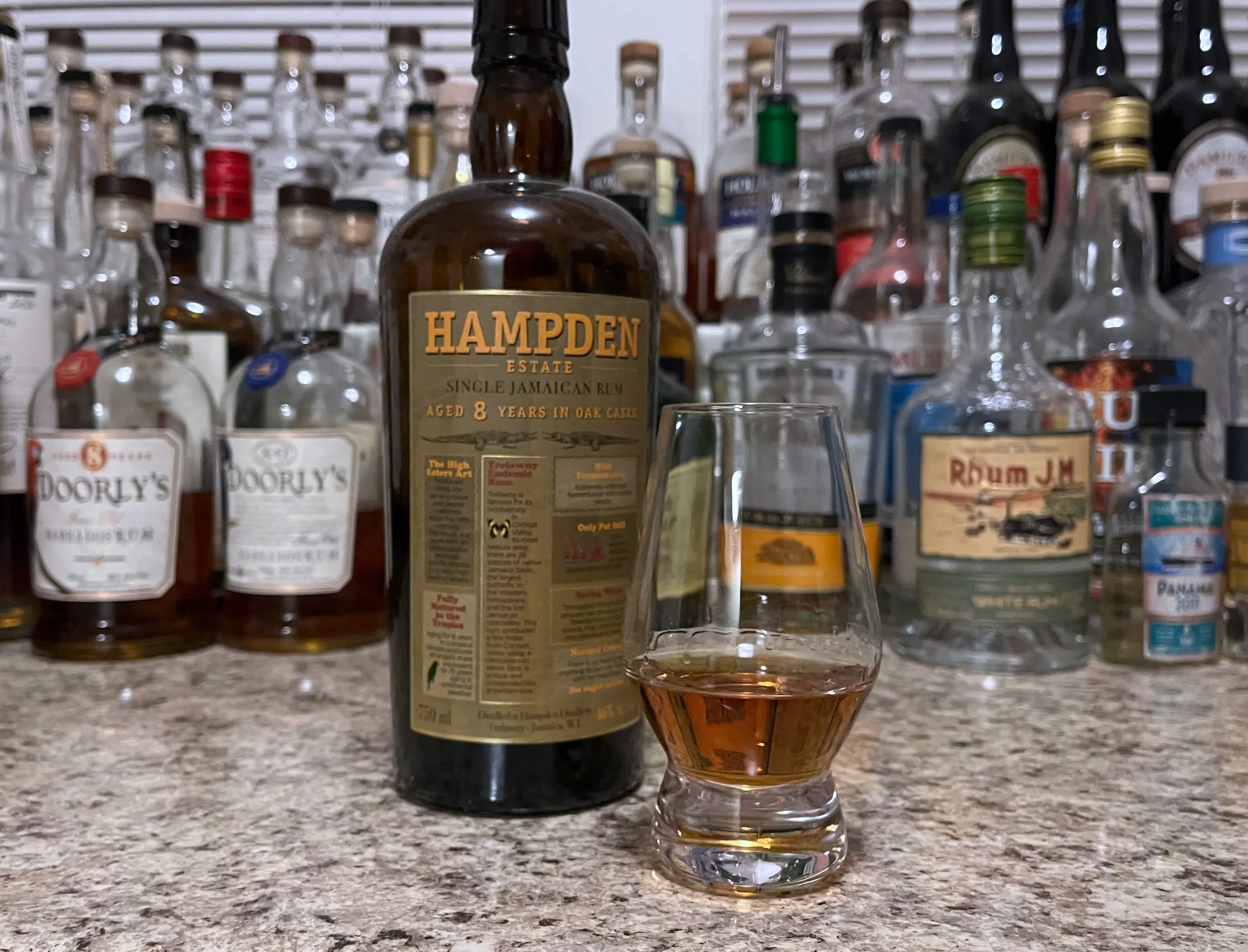 A bottle of Hampden 8 year next to a glencairn of rum on a kitchen counter