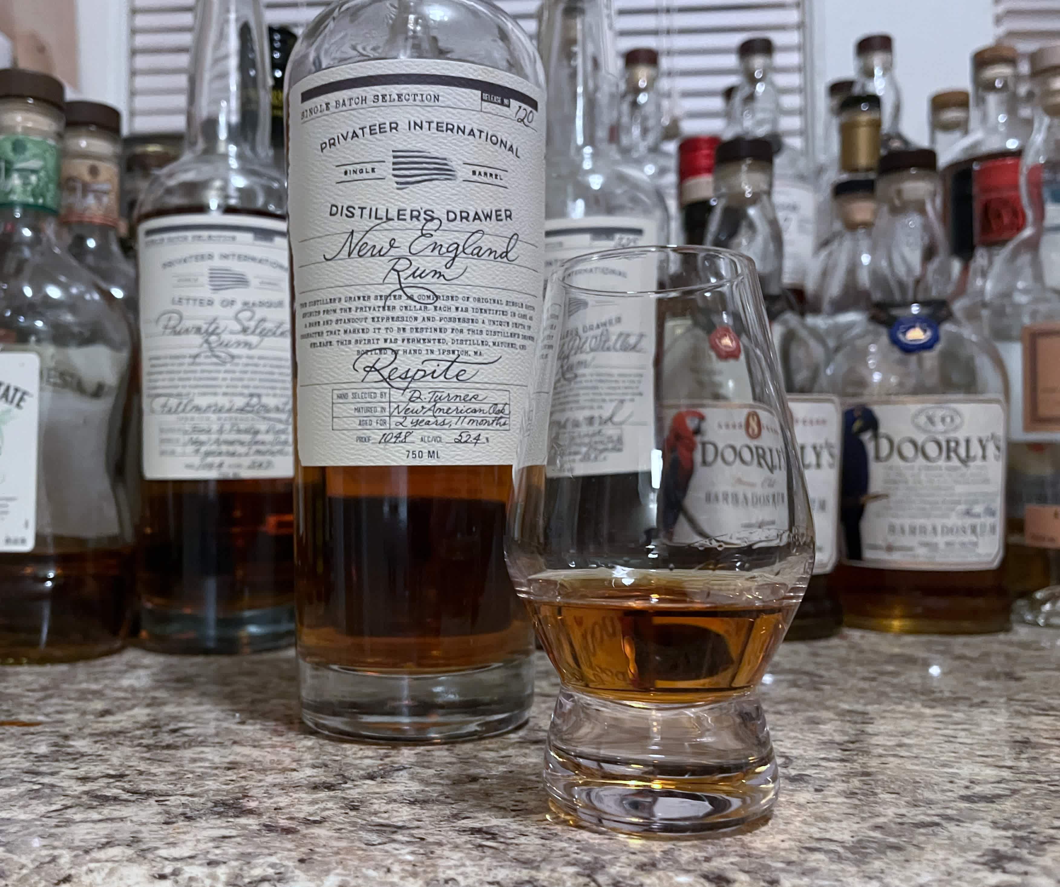 Privateer rum bottle sitting on a kitchen counter, next to a glencairn glass with rum in it