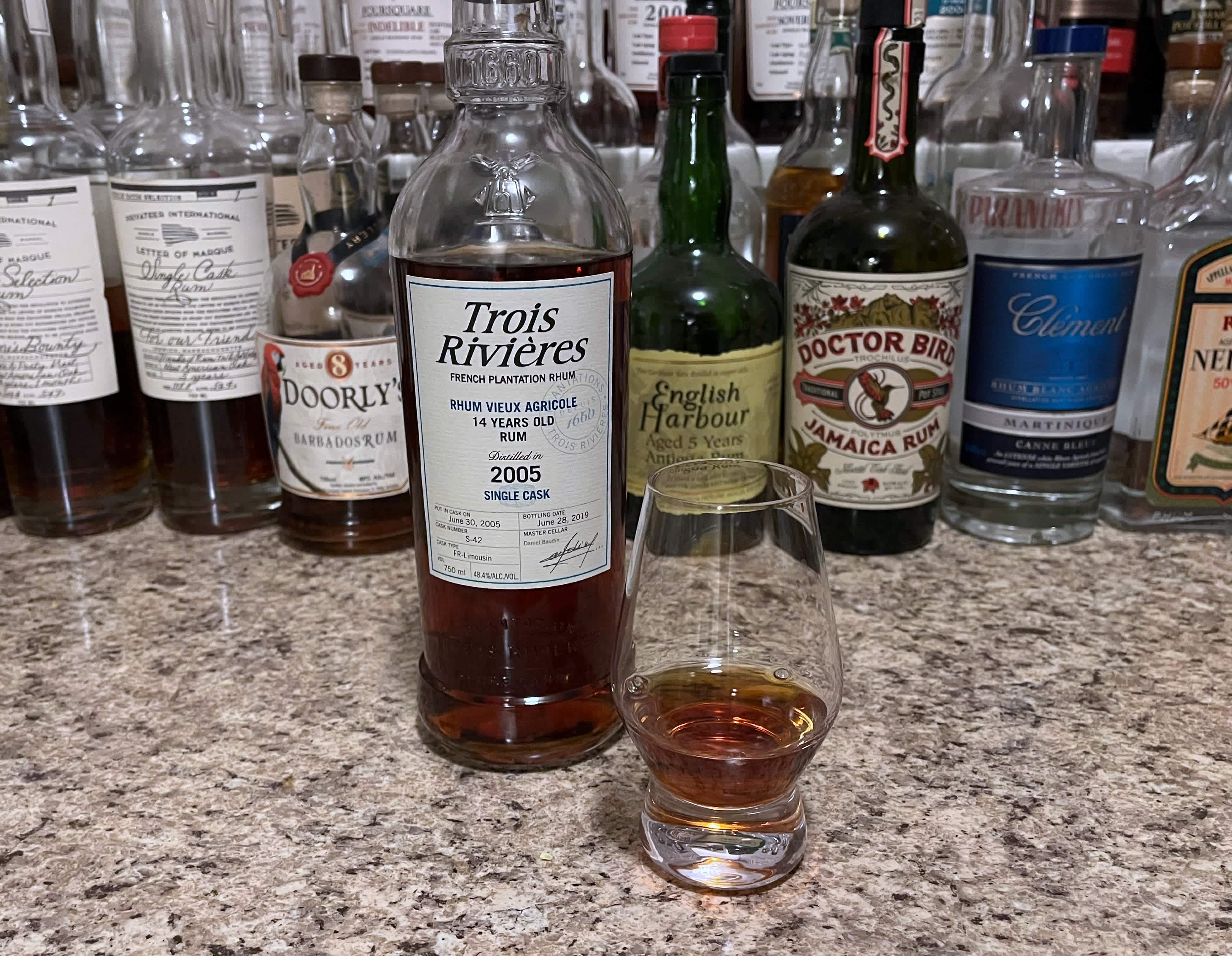 A bottle of Trois Rivières next to a glencairn of rum on a kitchen counter