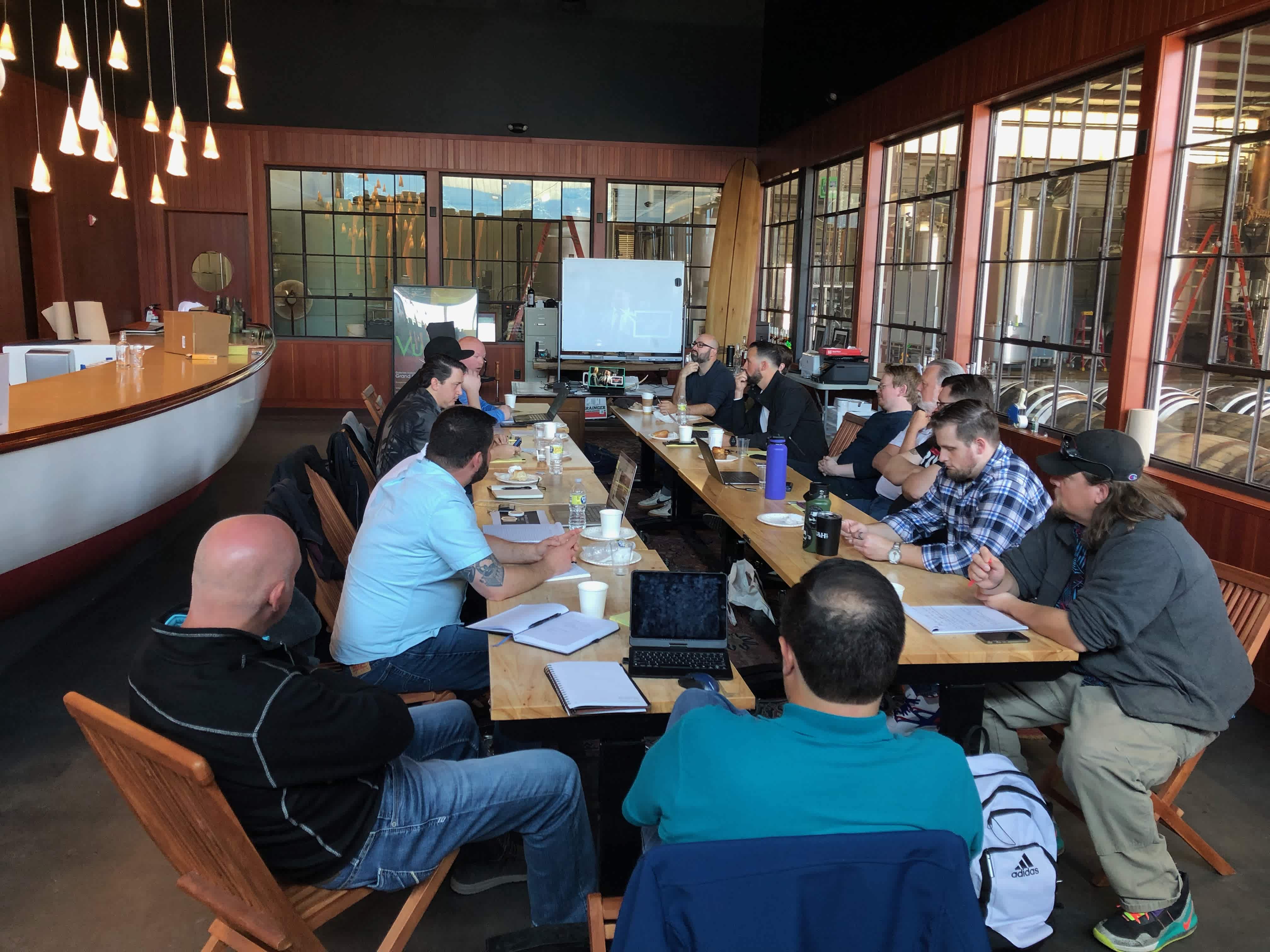 Group of people sitting around long conference tables in the office of Privateer's distillery