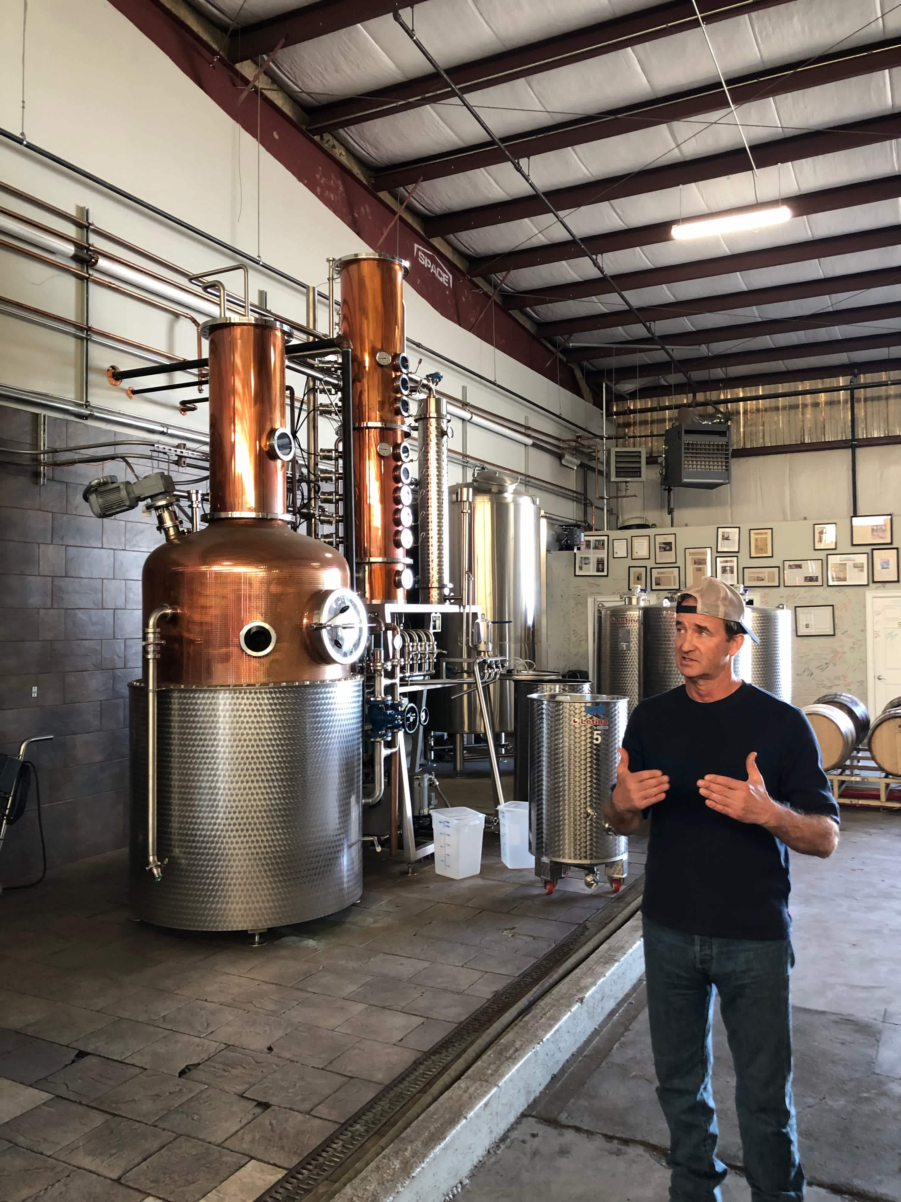 Andrew Cabot standing in front of copper hybrid still equipment