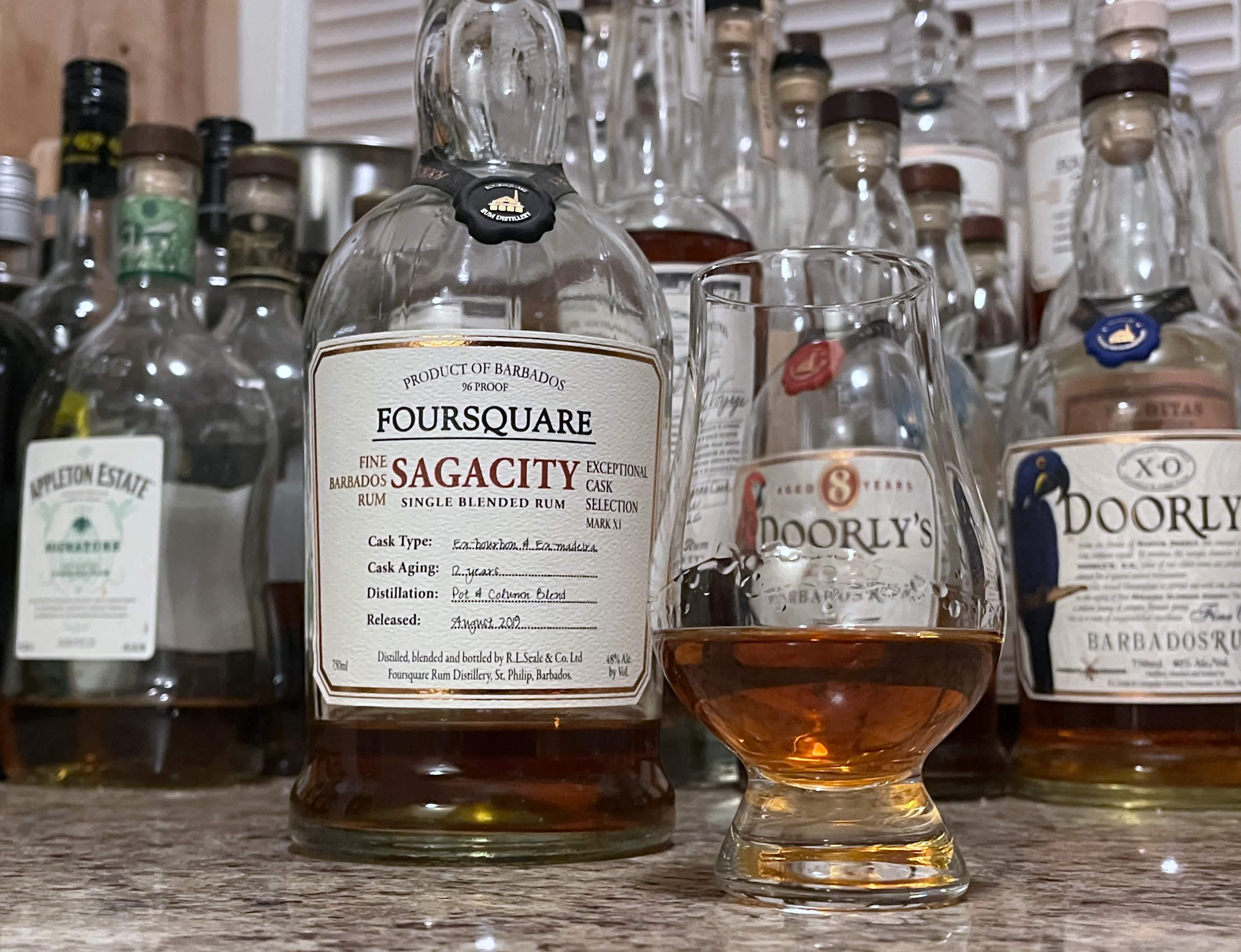 A bottle of Foursquare Sagacity next to a glencairn of rum on a kitchen counter