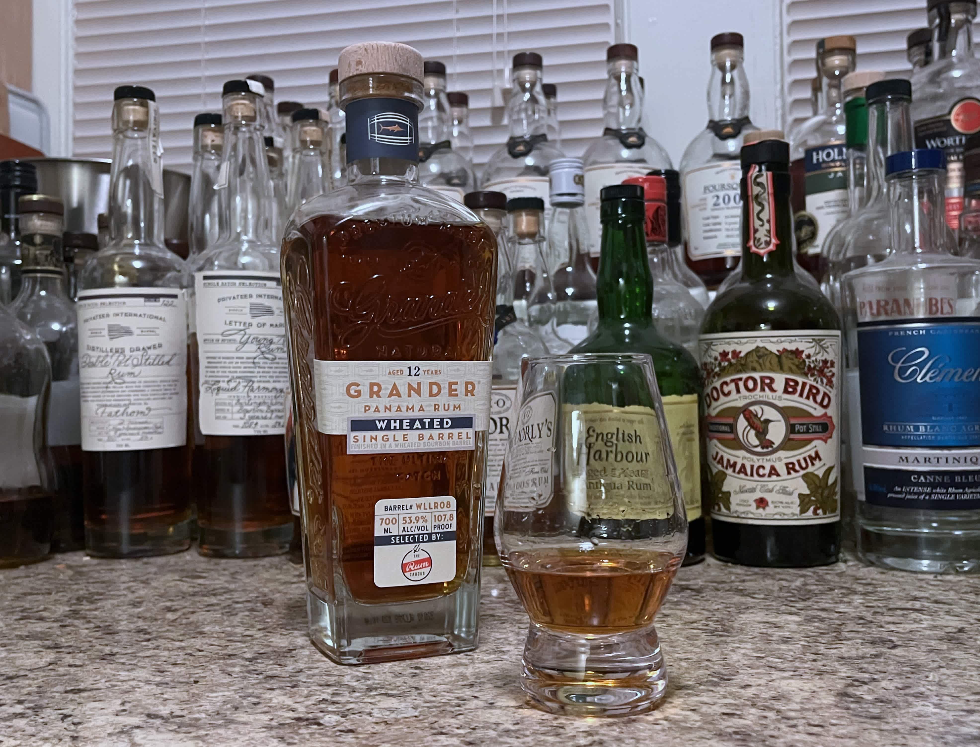 Bottle of Grander Wheated Single Barrel rum next to a glencairn of rum on a countertop