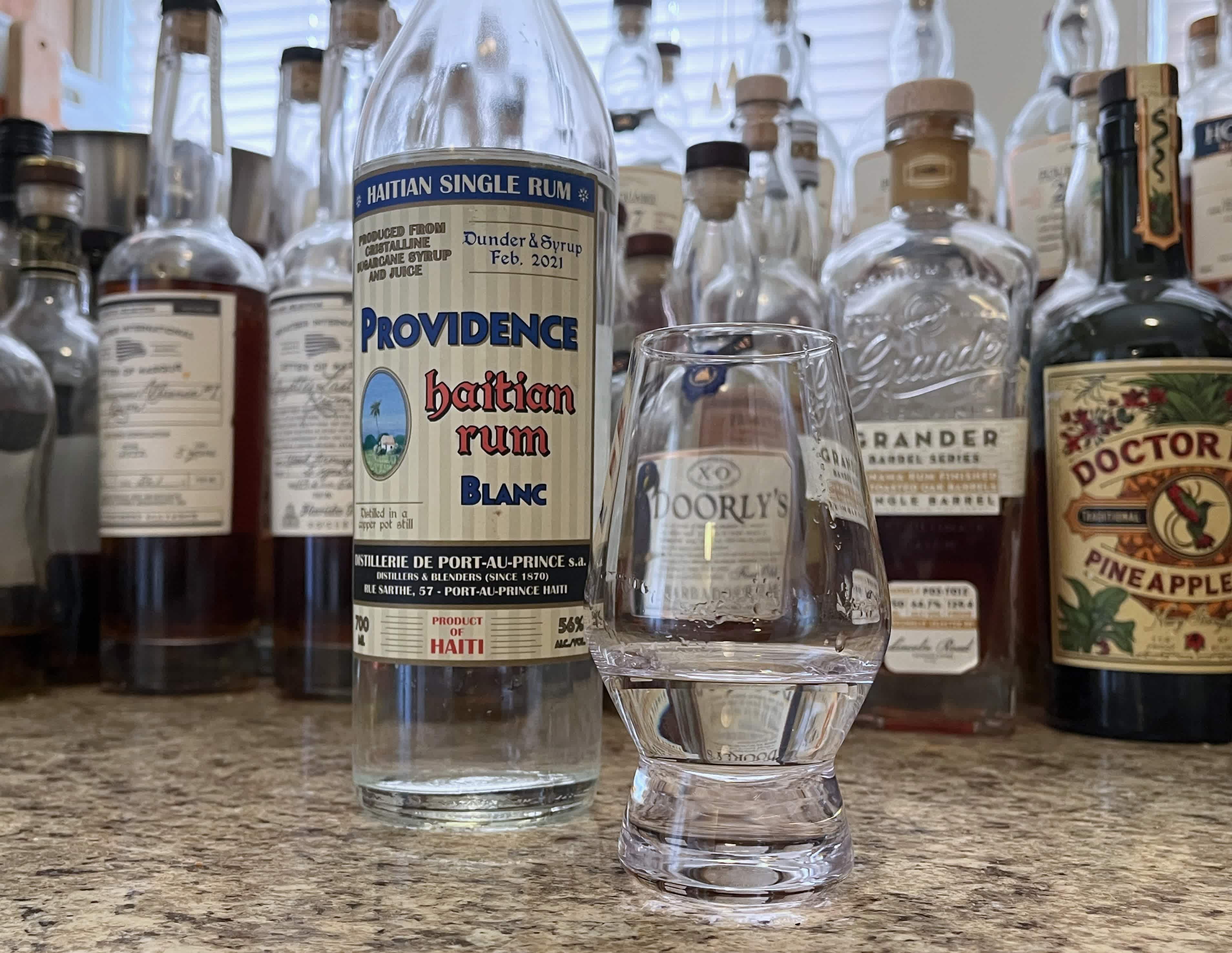 A bottle of Providence Dunder & Syrup next to a glencairn of rum on a kitchen counter