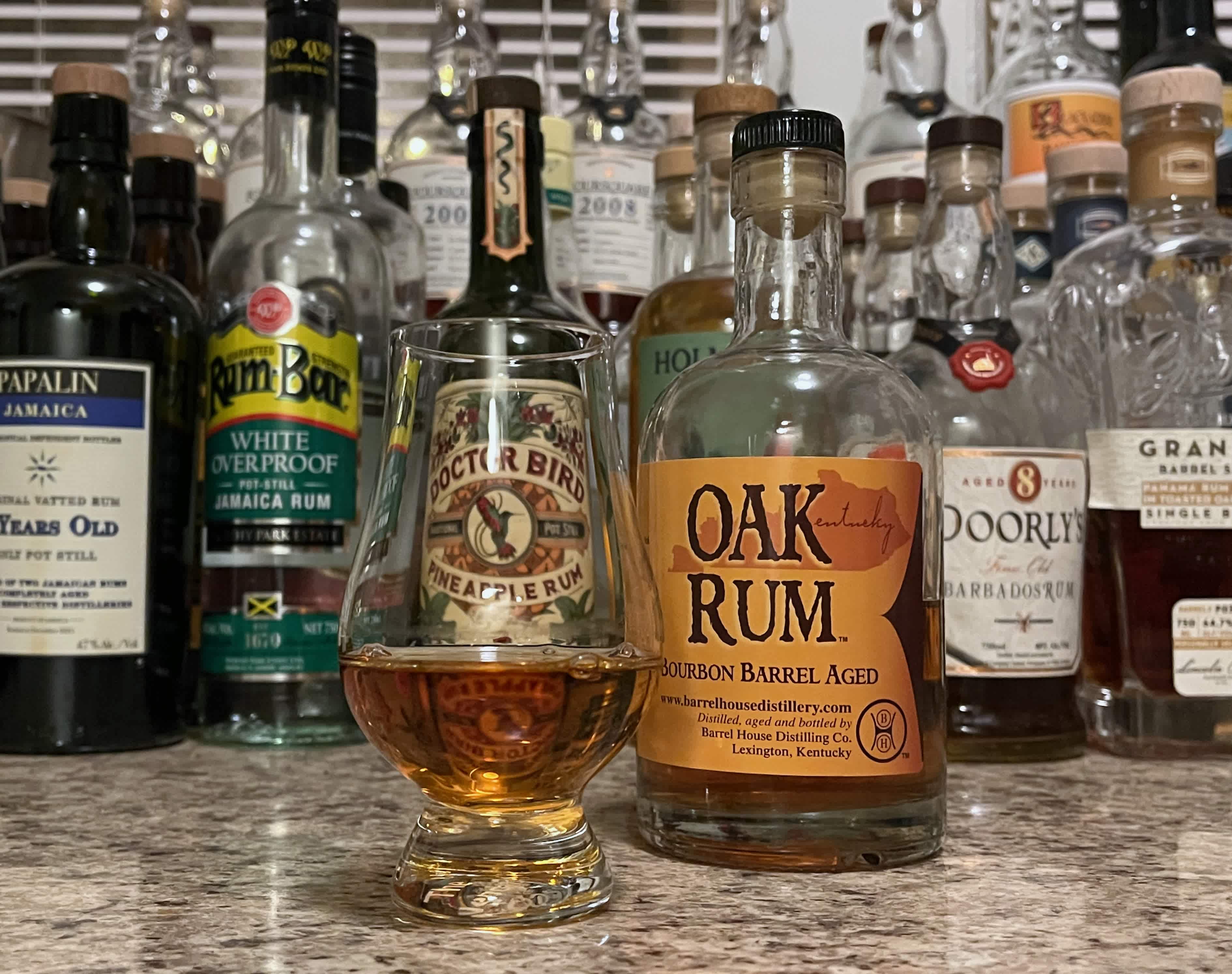 Bottle of Barrel House Oak Rum rum next to a glencairn of rum on a countertop