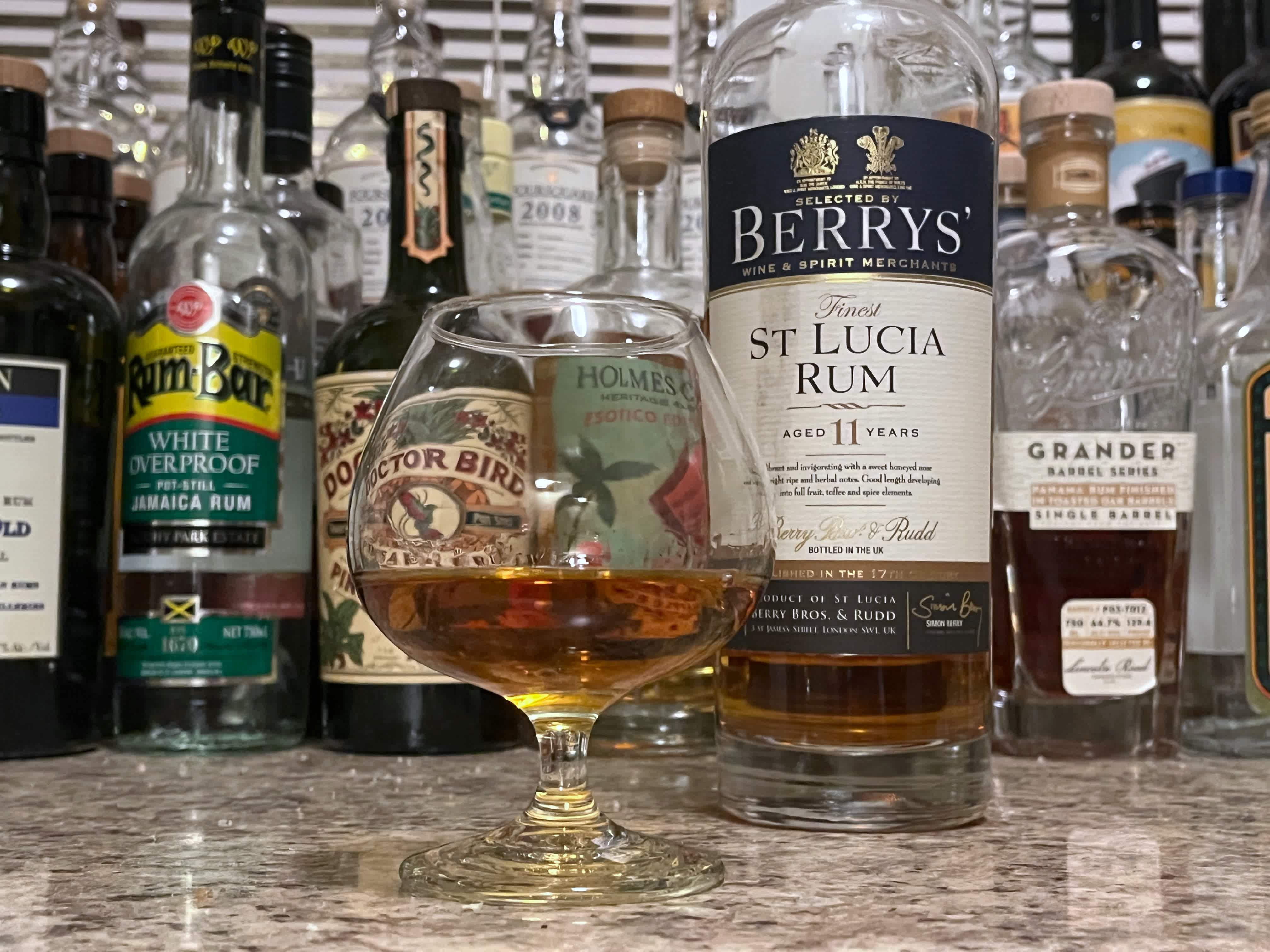 A bottle of Berrys' St Lucia next to a glencairn of rum on a kitchen counter