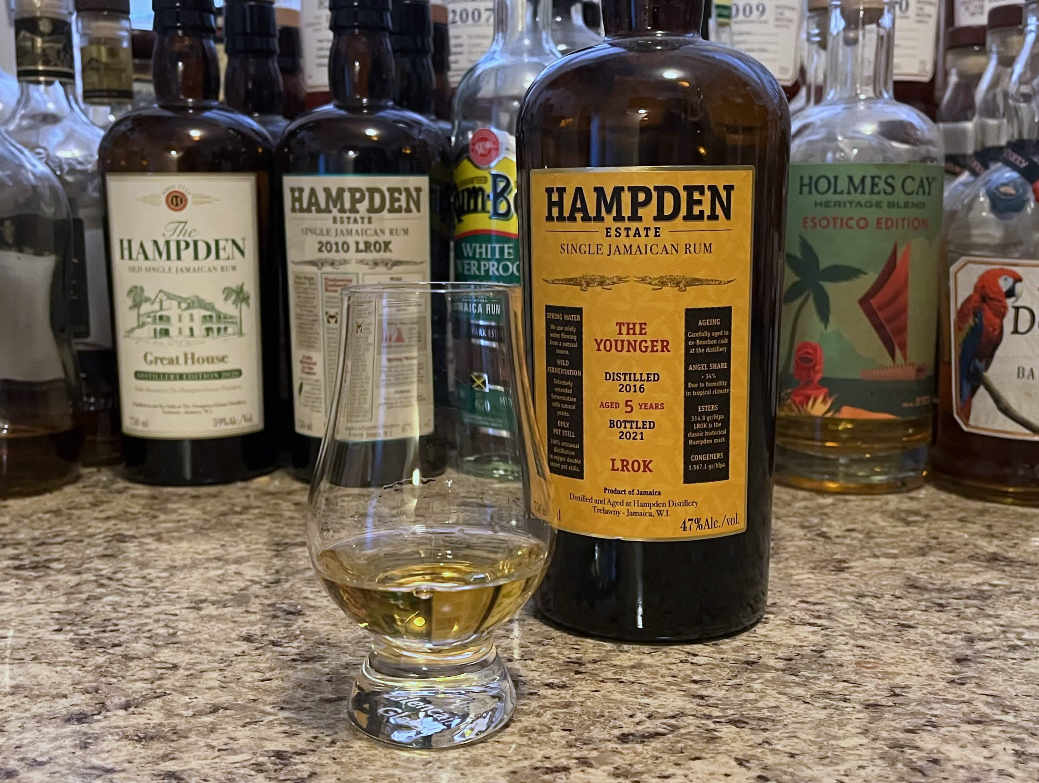 A bottle of Hampden LROK The Younger next to a glencairn of rum on a kitchen counter