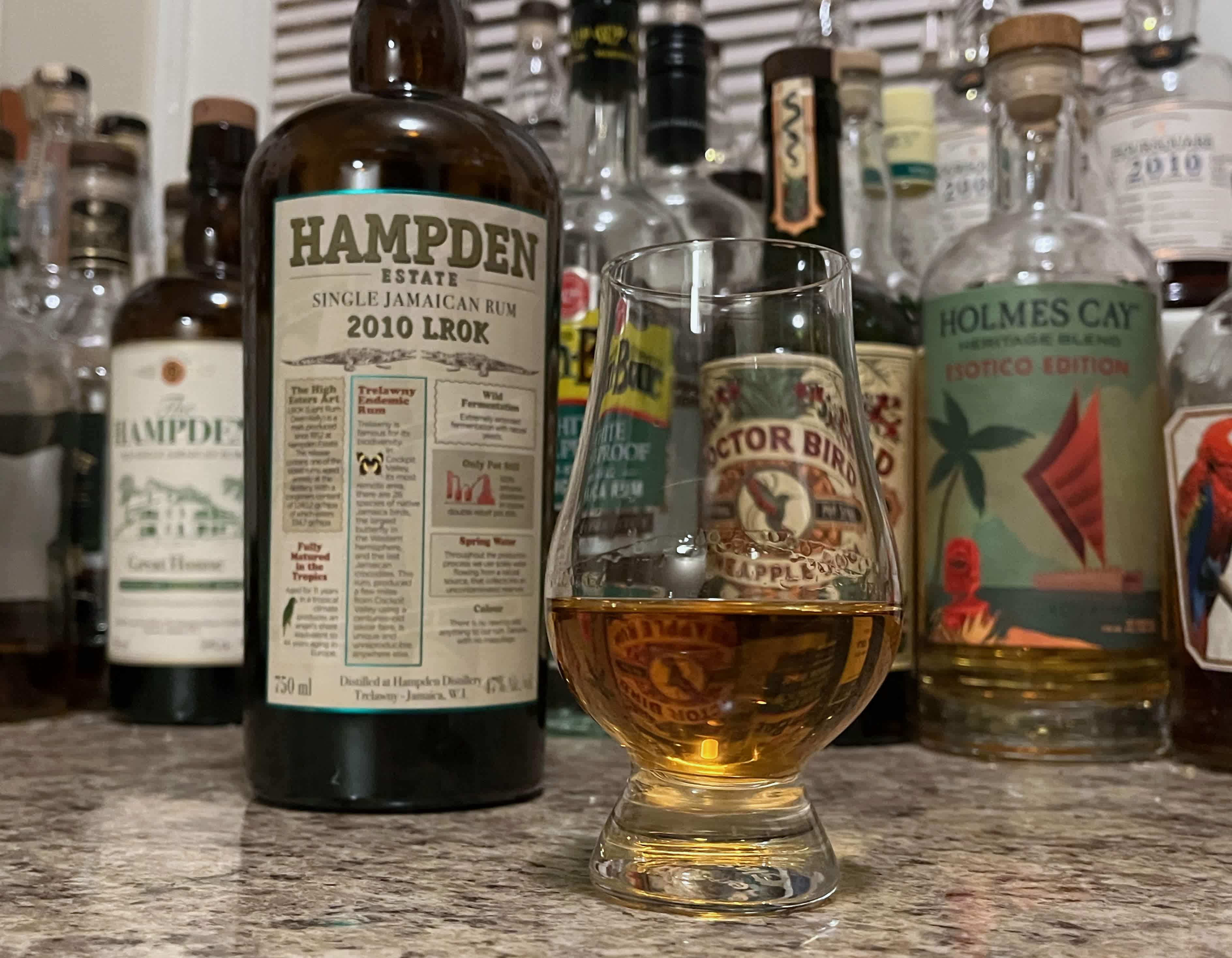 A bottle of Hampden 2010 LROK next to a glencairn of rum on a kitchen counter