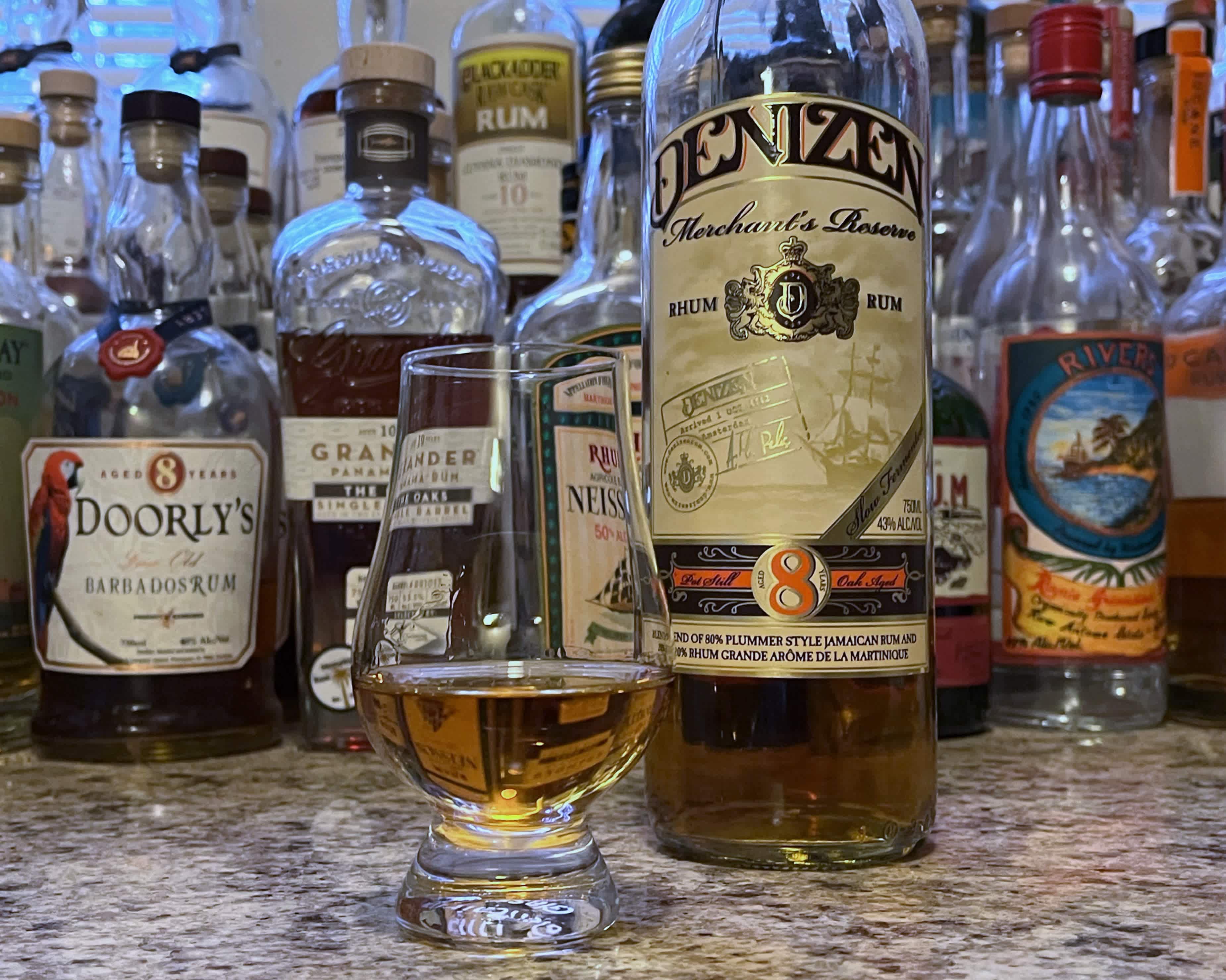 A bottle of Denizen Merchant's Reserve next to a glencairn of rum