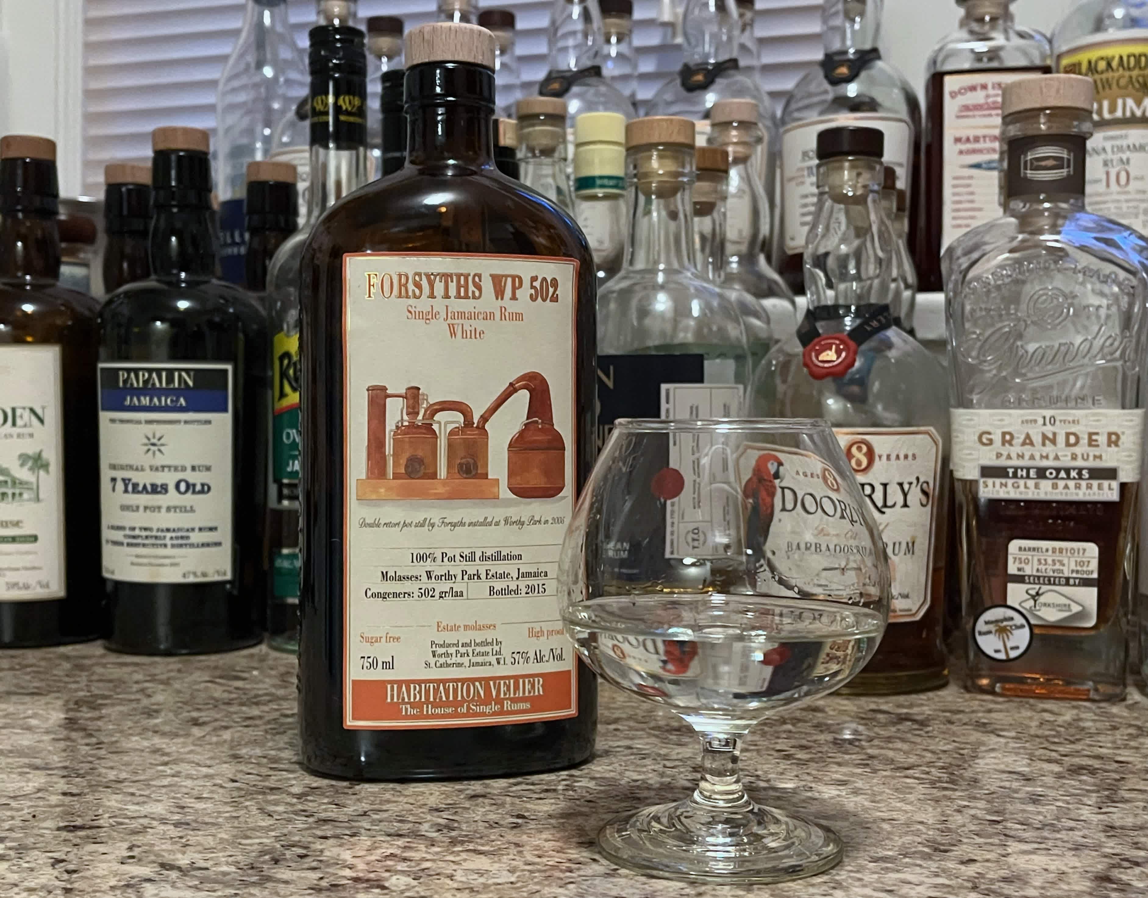 Bottle of Habitation Velier Forsyths WP 502 next to a glass of rum