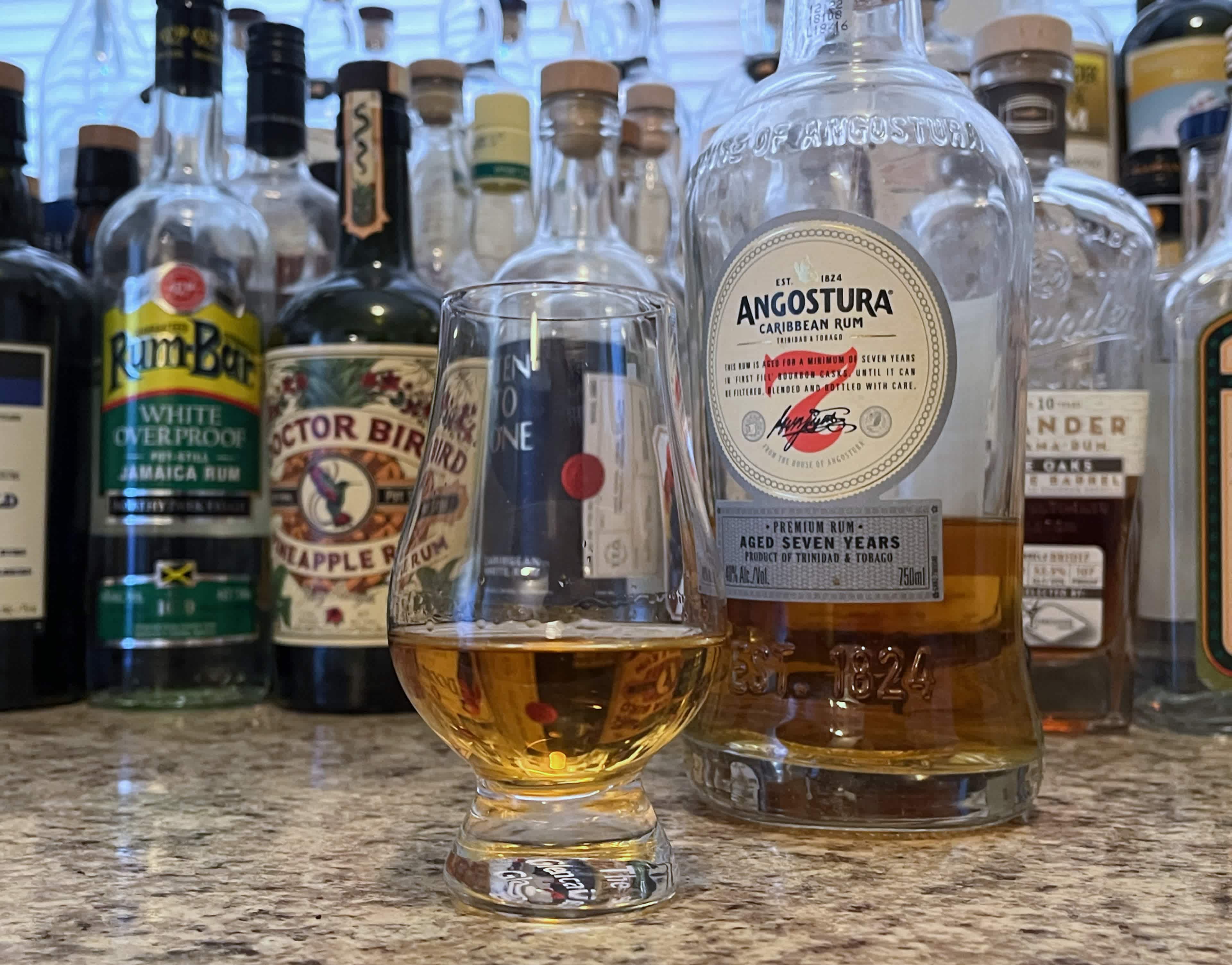 A bottle of Angostura 7 next to a glencairn of rum