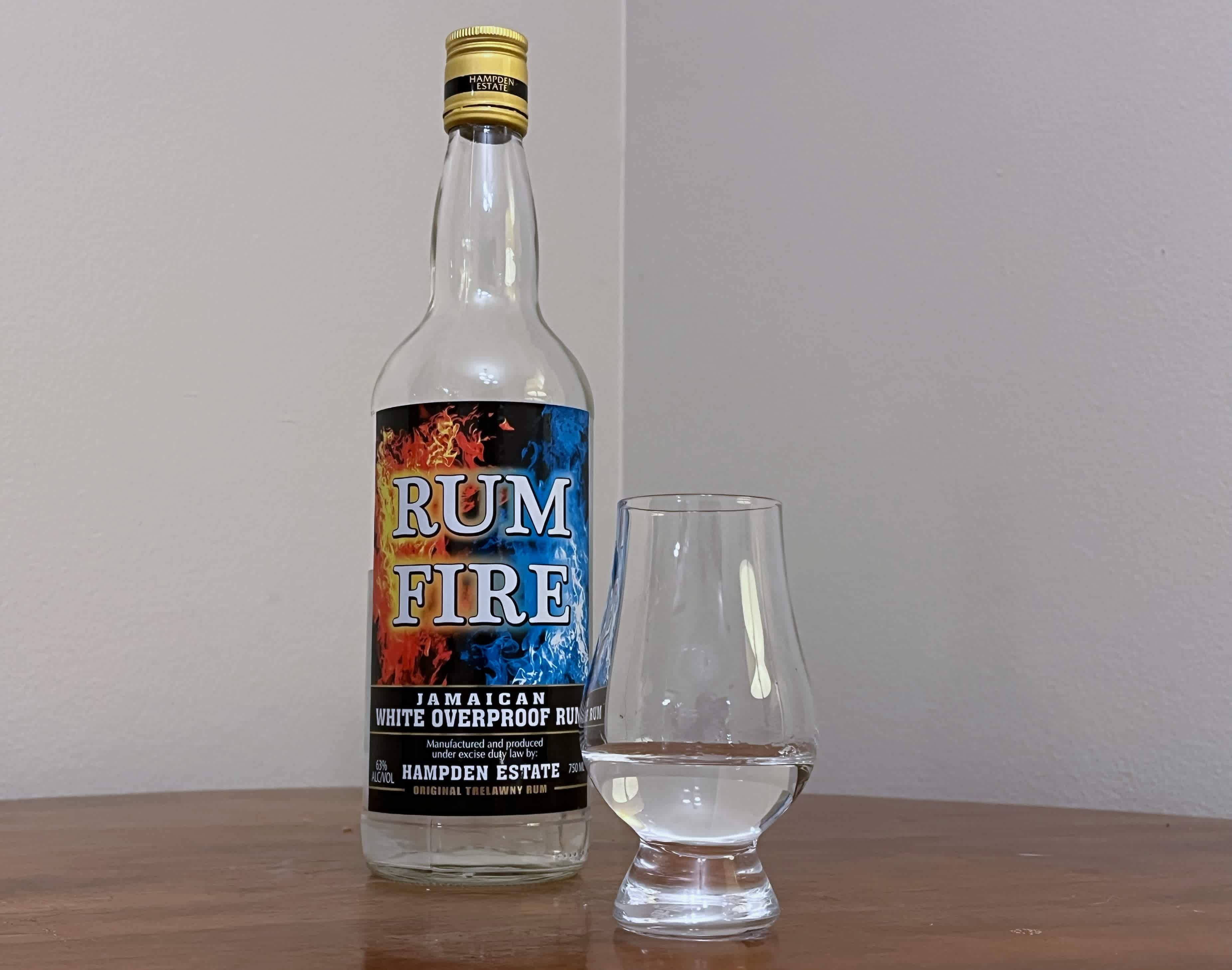 A bottle of Rum Fire next to a glass of rum on a tabletop