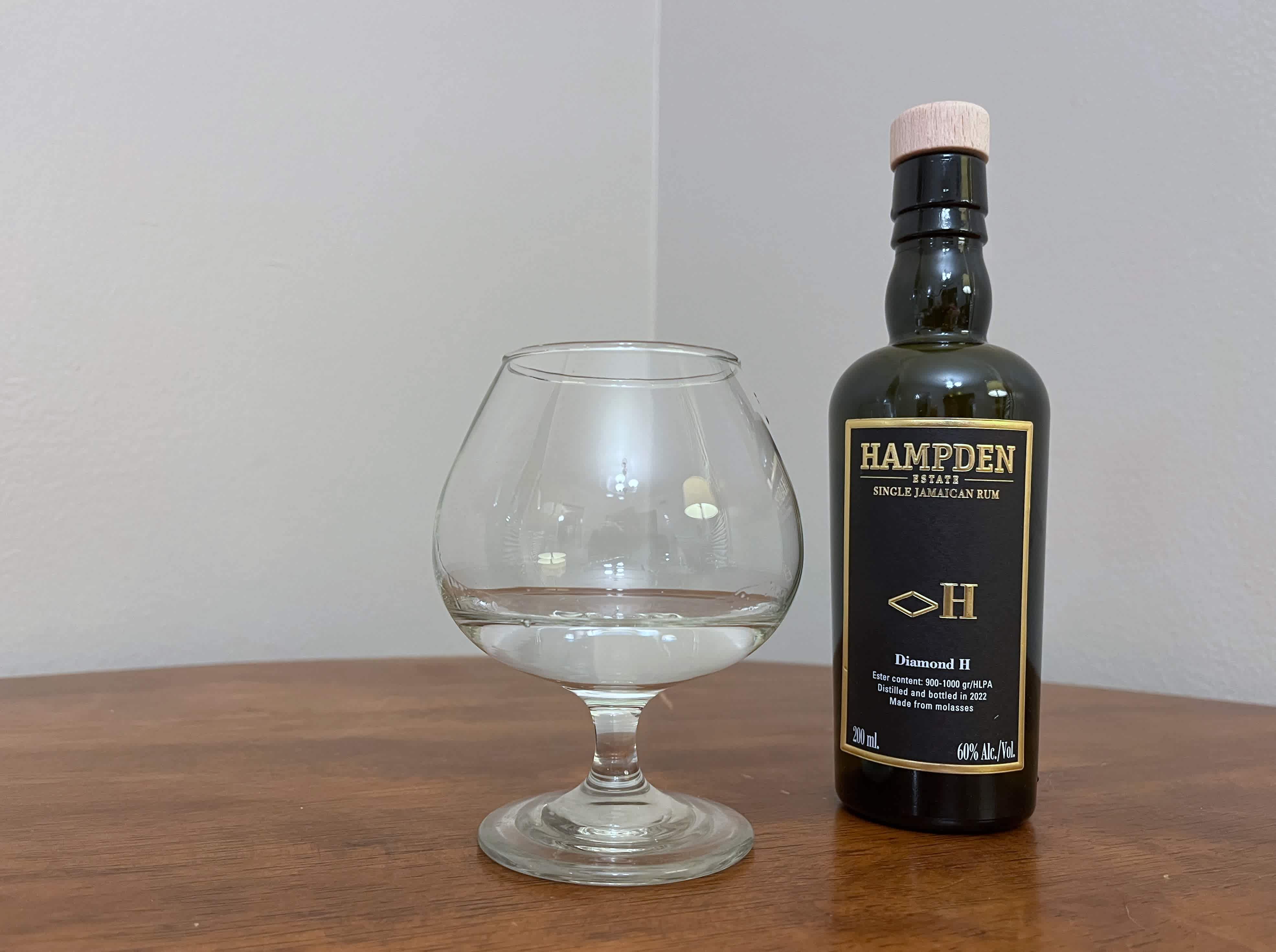 A bottle of Hampden 8 Marks <>H next to a glass of rum