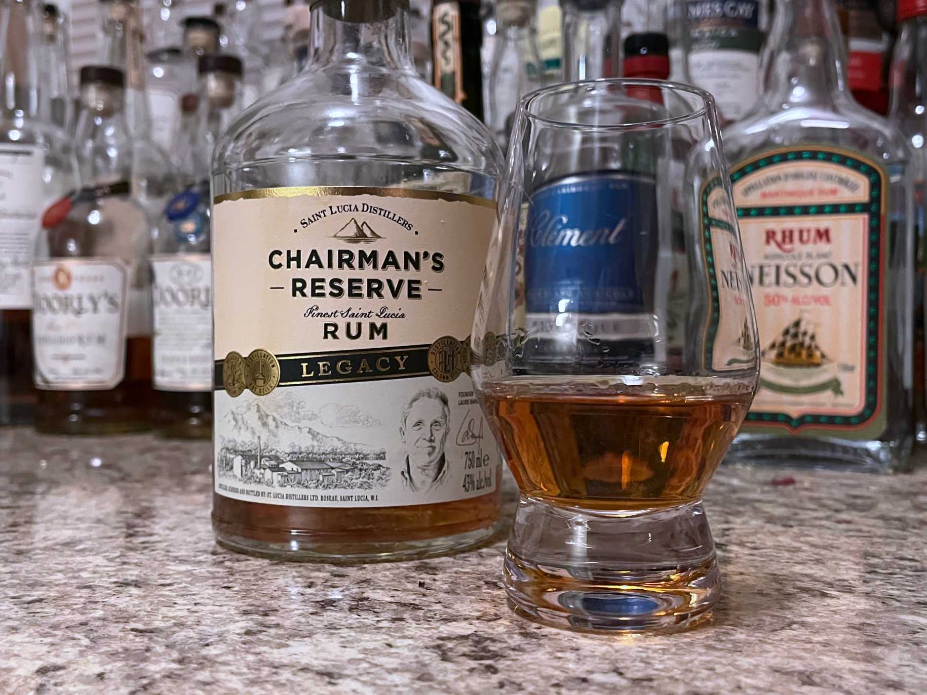 A bottle of Chairman's Reserve Legacy next to a glencairn of rum on a kitchen counter