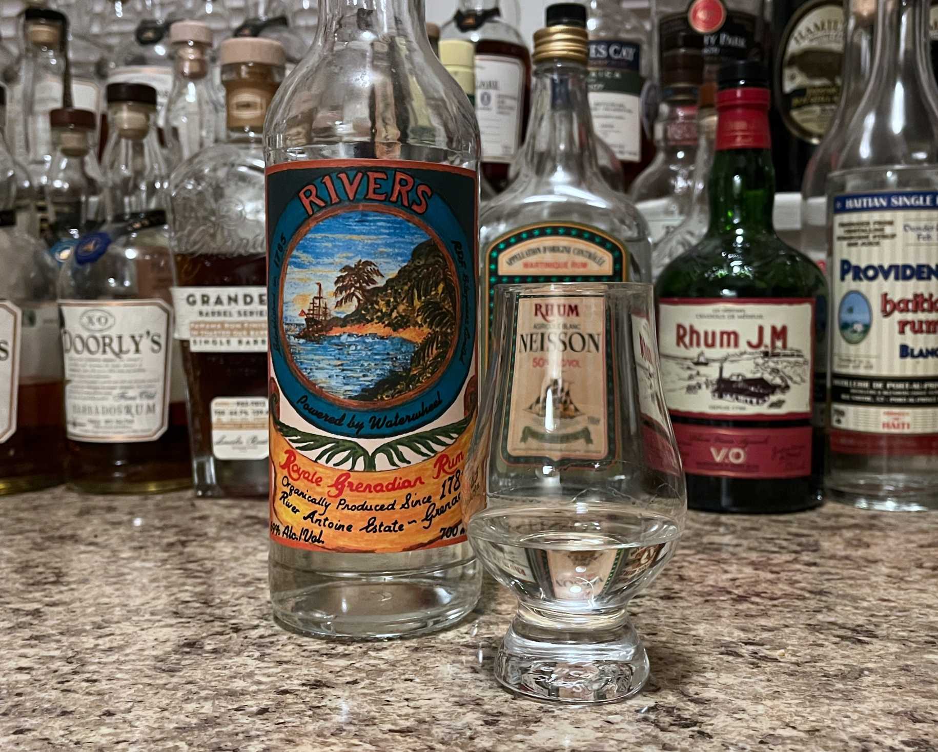 A bottle of Rivers next to a glencairn of rum on a kitchen counter