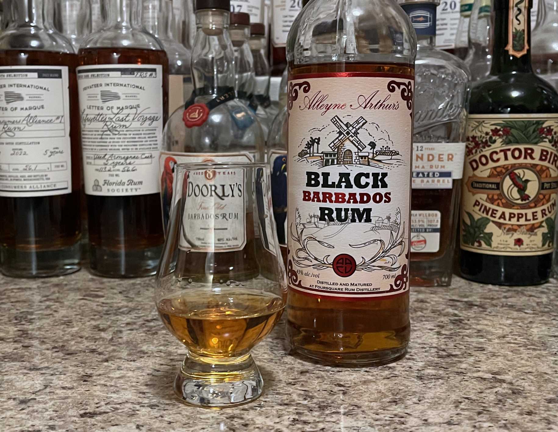 A bottle of Black Barbados Rum next to a glencairn of rum on a kitchen counter