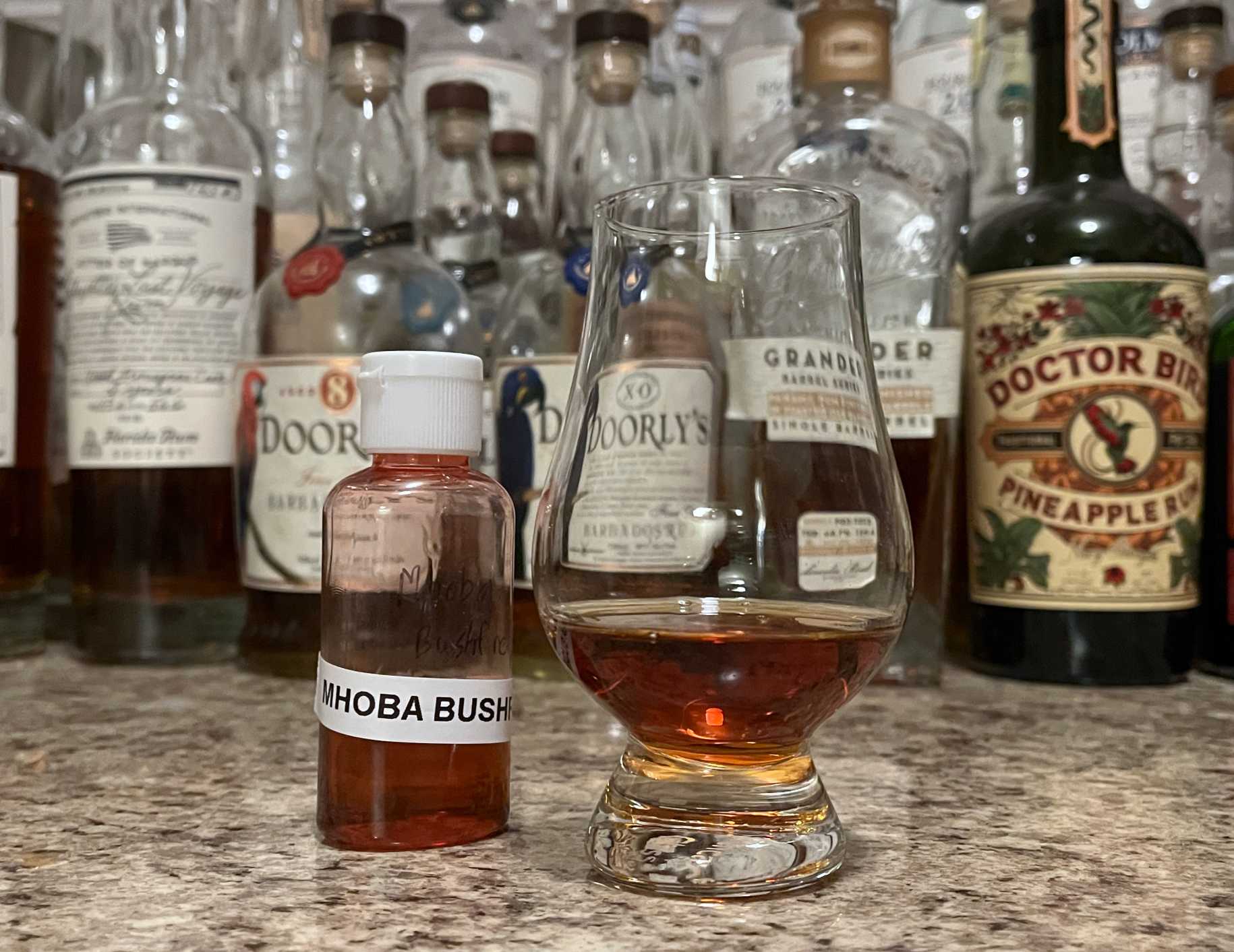 Sample bottle of Mhoba Bushfire on a counter next to a glencairn with rum poured in it