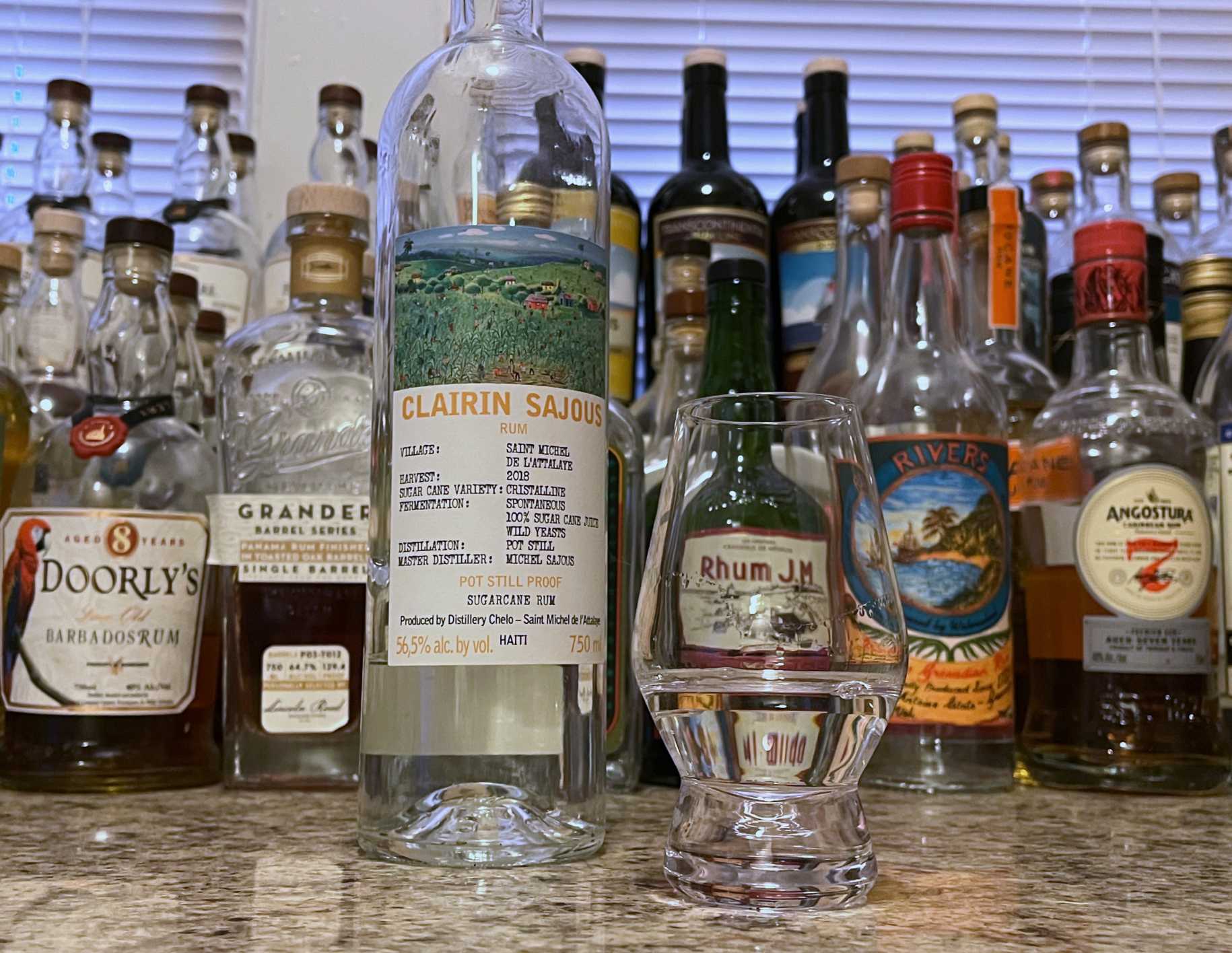 Bottle of Clairin Sajous rum next to a glencairn of rum on a countertop