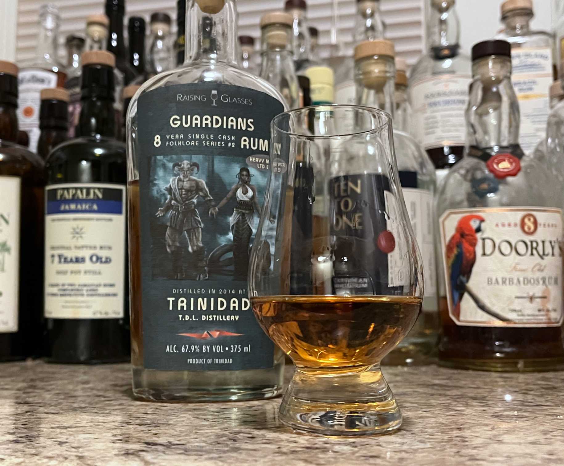 Raising Glasses Guardians bottle next to a glass of rum