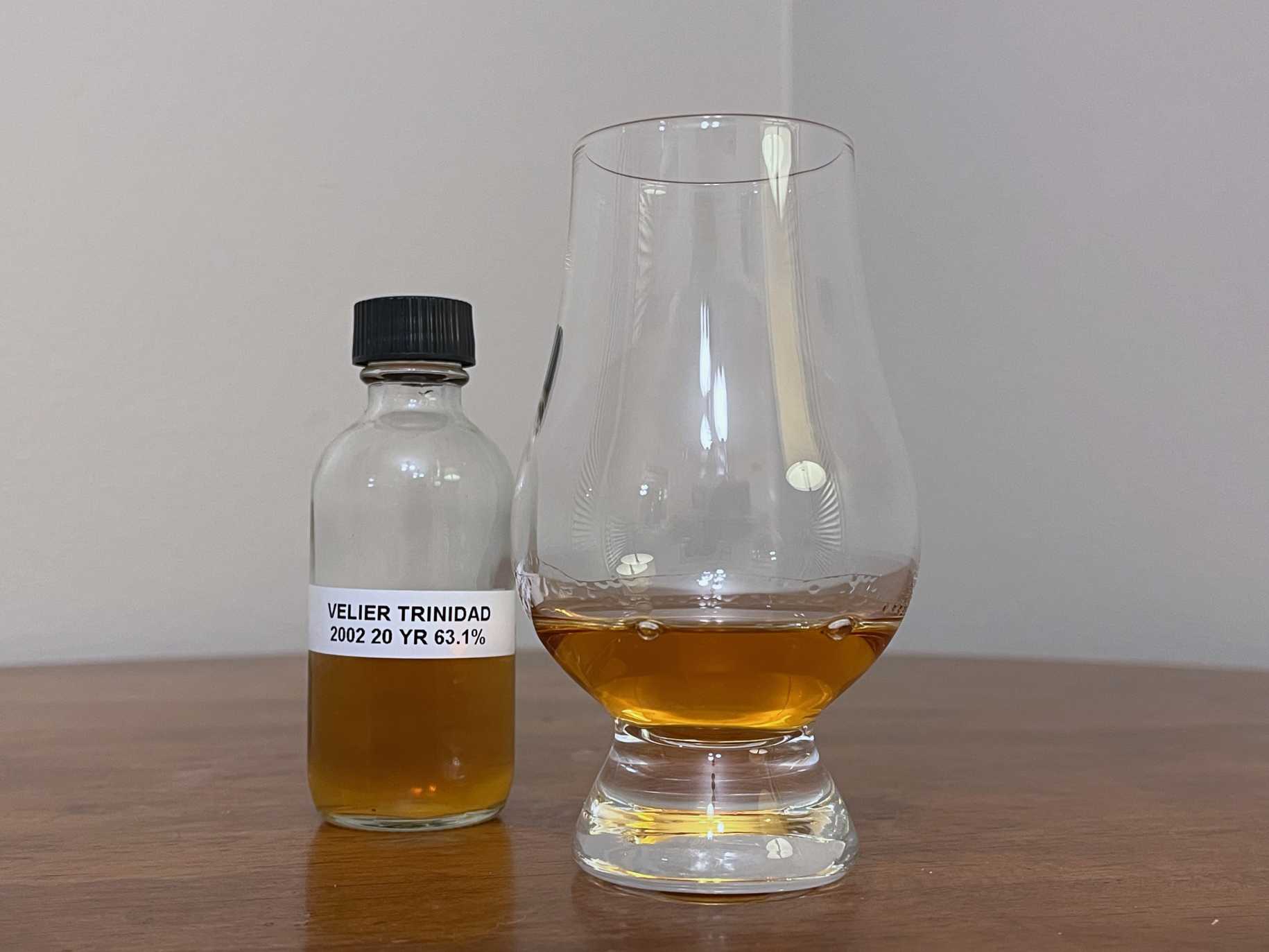 A bottle of La Maison & Velier Flag Series Trinidad next to a glass of rum on a tabletop