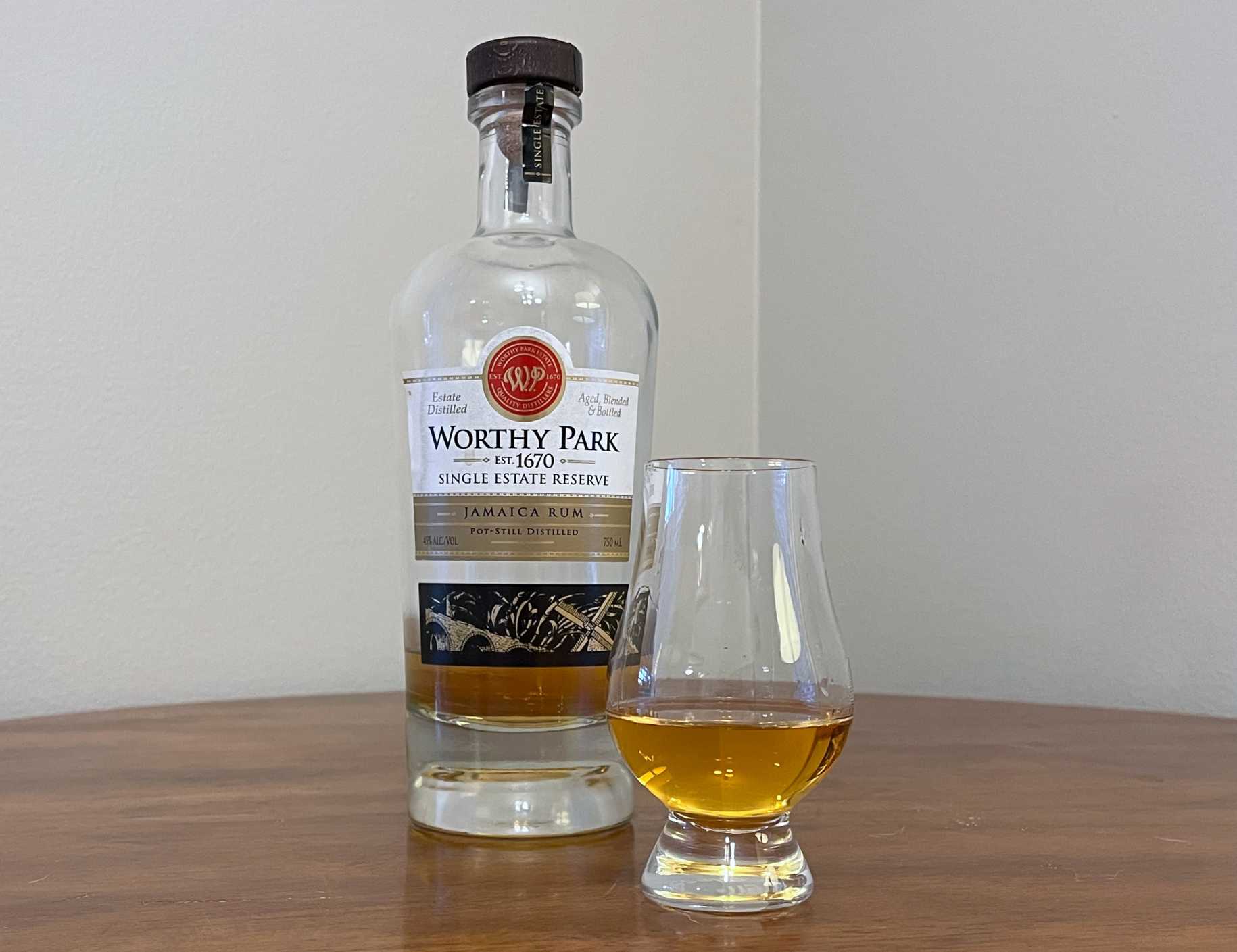 Bottle of Worthy Park Single Estate Reserve next to a glass of rum on a tabletop