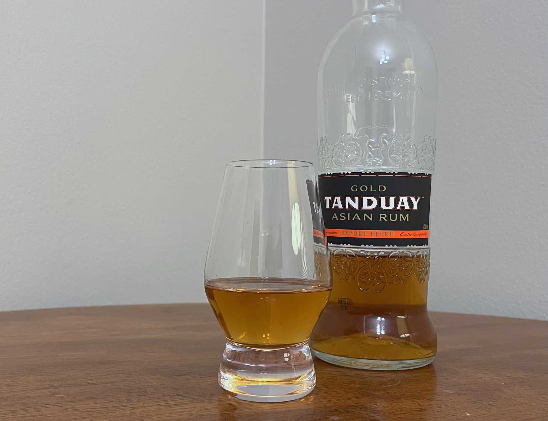 A bottle of Tanduay Gold Asian Rum next to a glass of rum