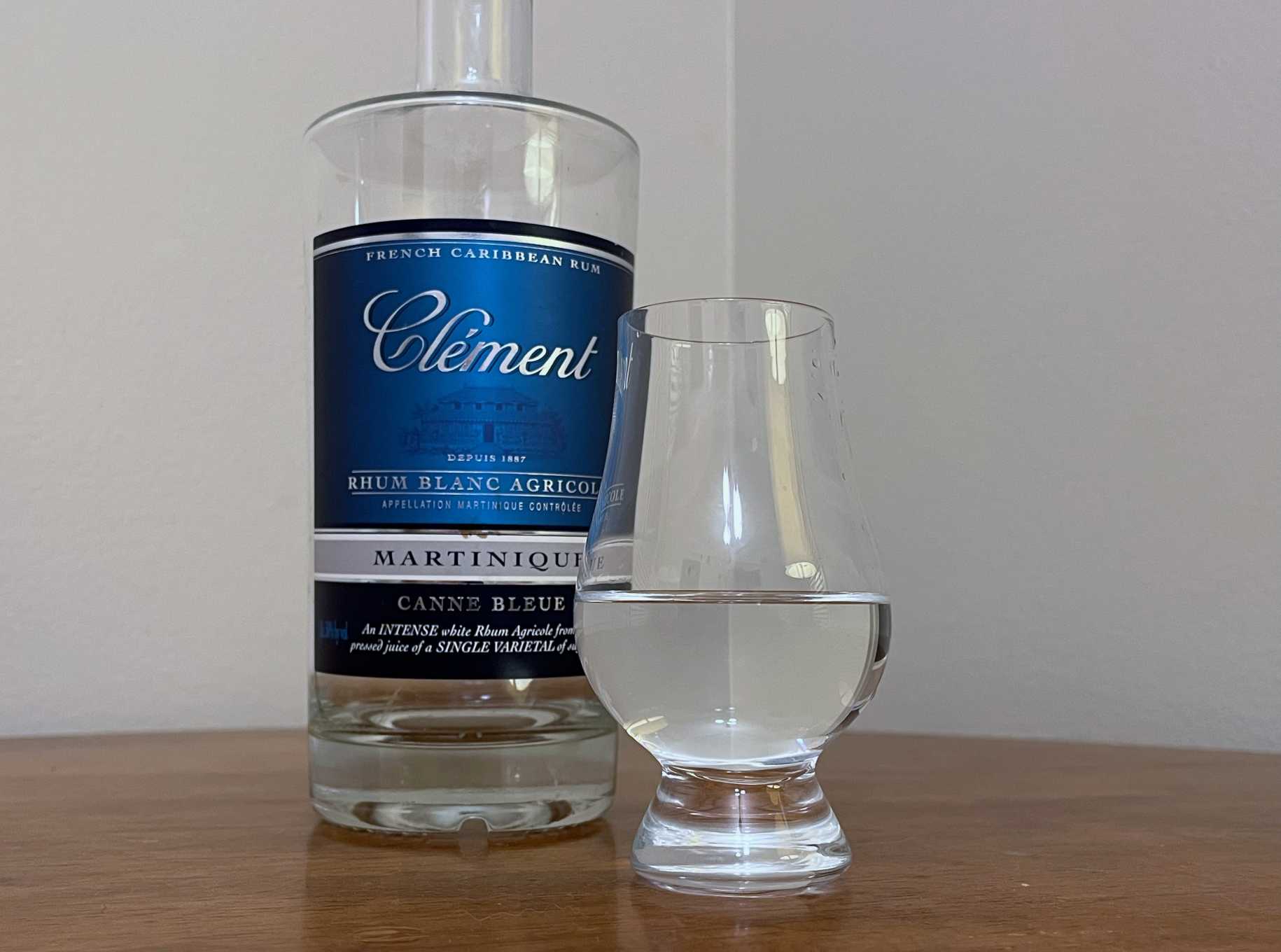 A bottle of Clément Canne Bleue next to a glass of rum