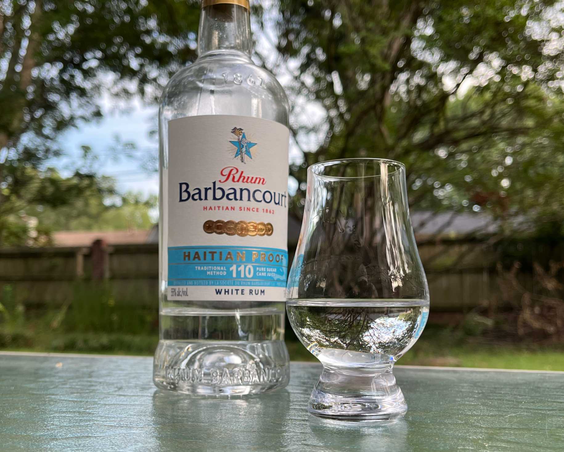 A bottle of Rhum Barbancourt Haitian Proof next to a glass of rum