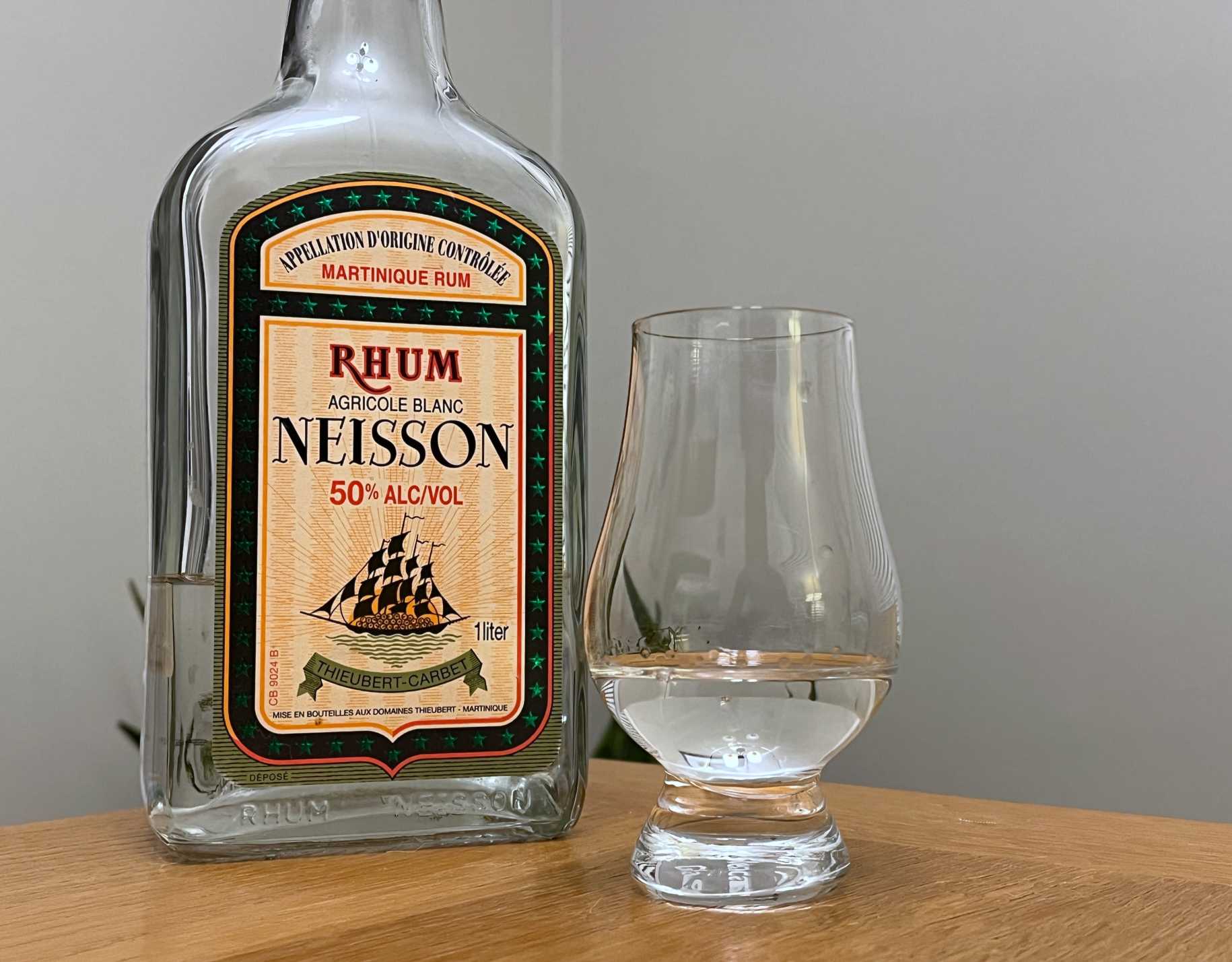 A bottle of Neisson Blanc next to a glass of rum