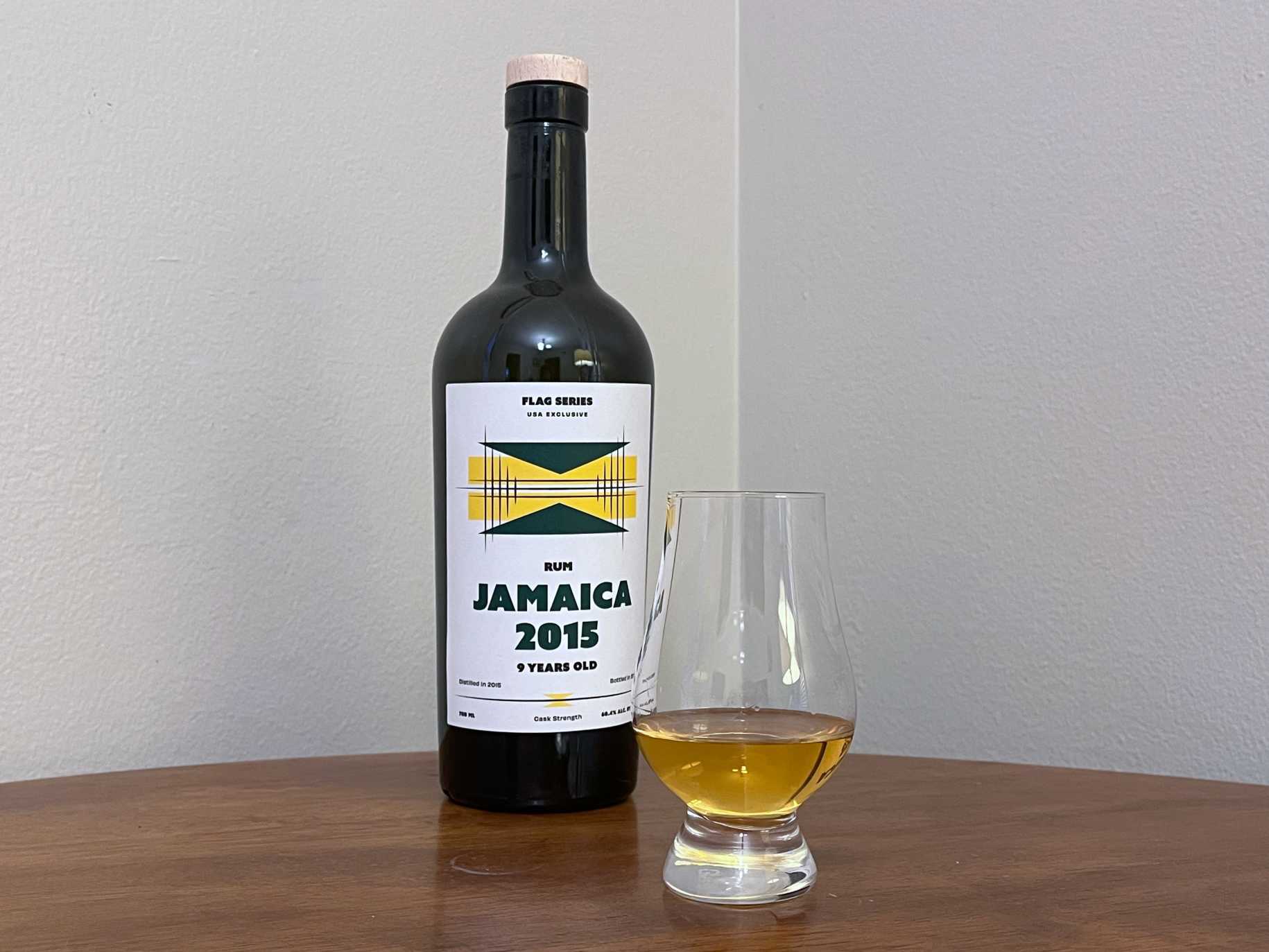 A bottle of Flag Series Jamaica 2015 9 year next to a glass of rum