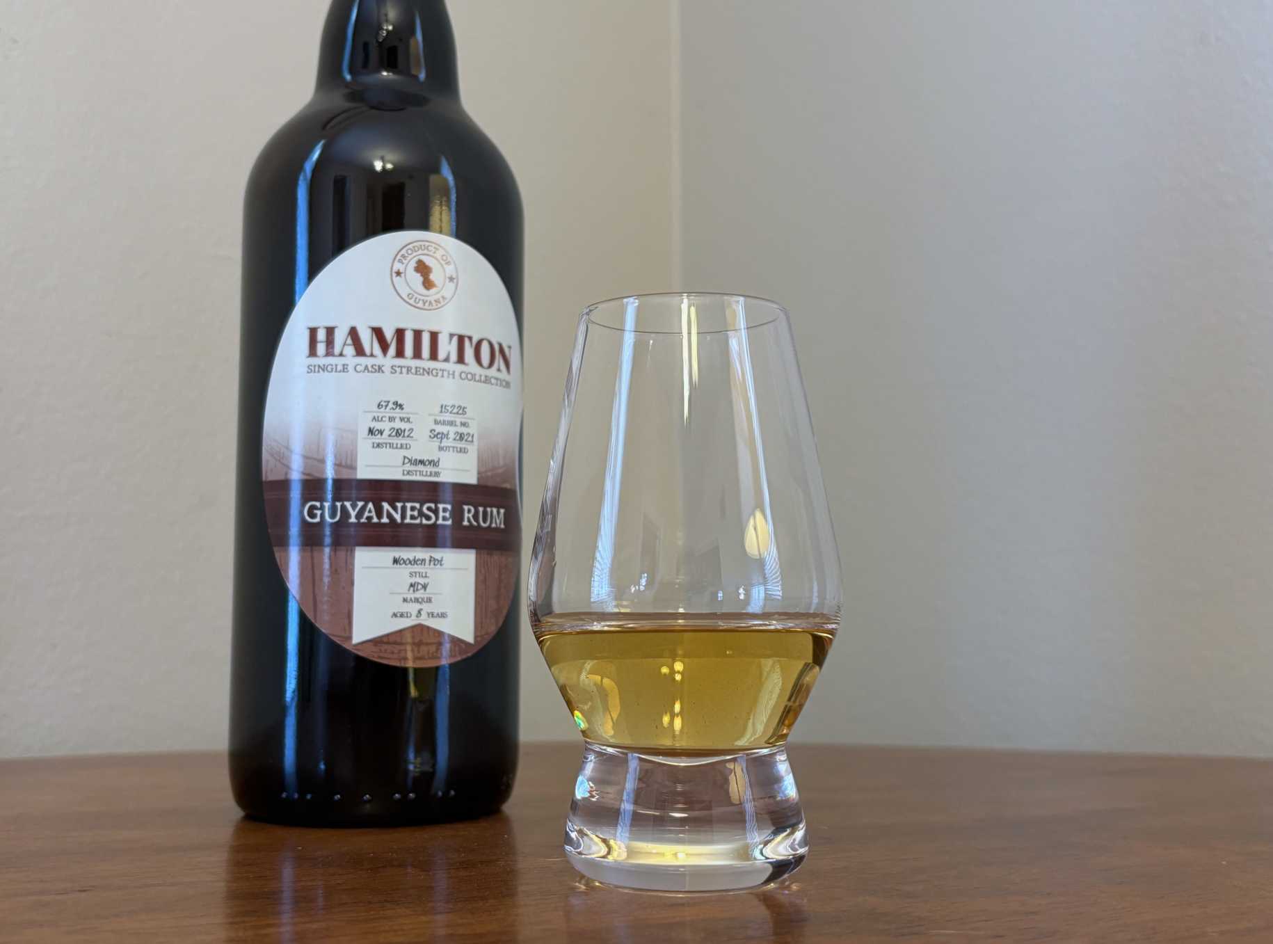 A bottle of Hamilton Single Cask Strength Collection Guyanese Rum Versailles 8 year next to a glass of rum